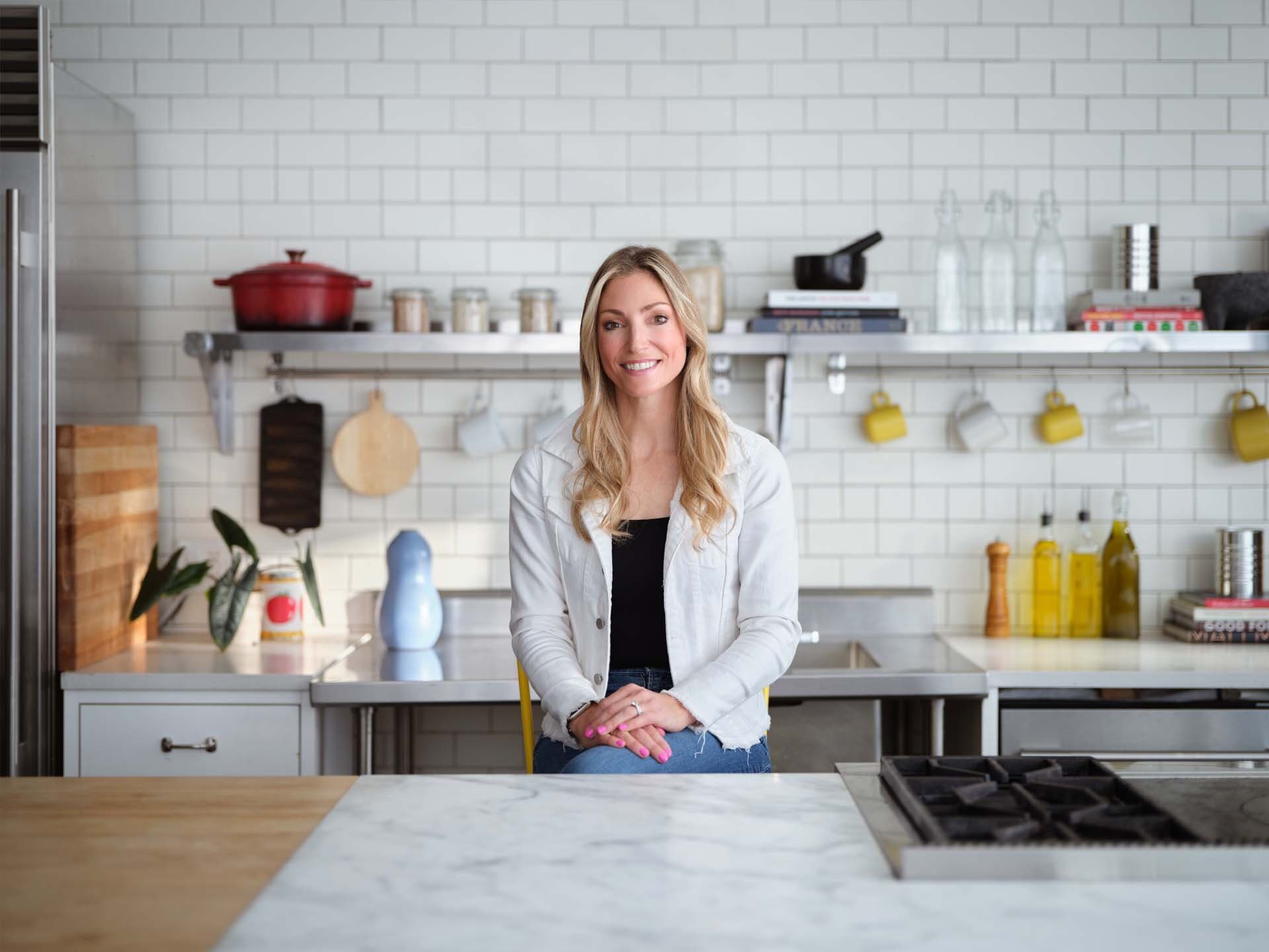 Smiling person with blond hair standing in a bright kitchen