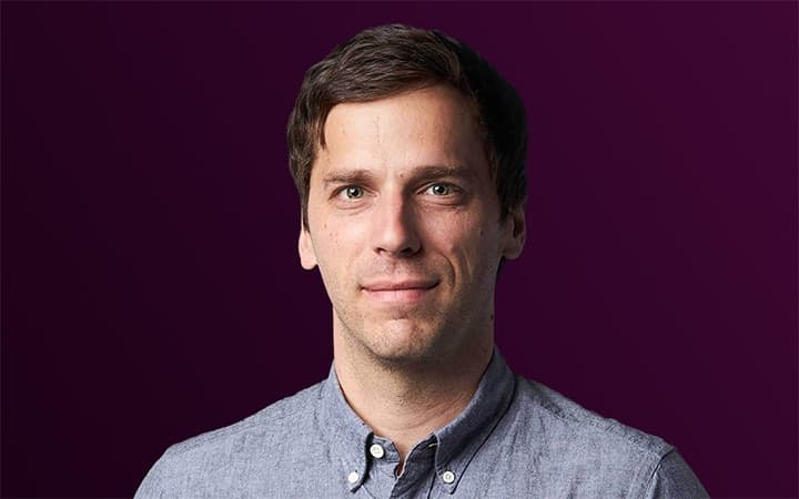 Serious person in a button-up shirt on purple.