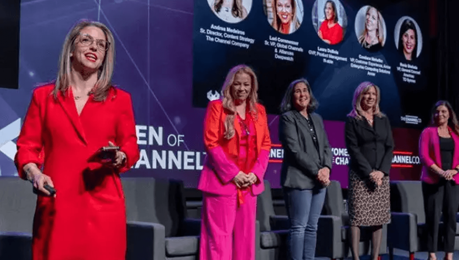 Five people onstage, including one speaking in red