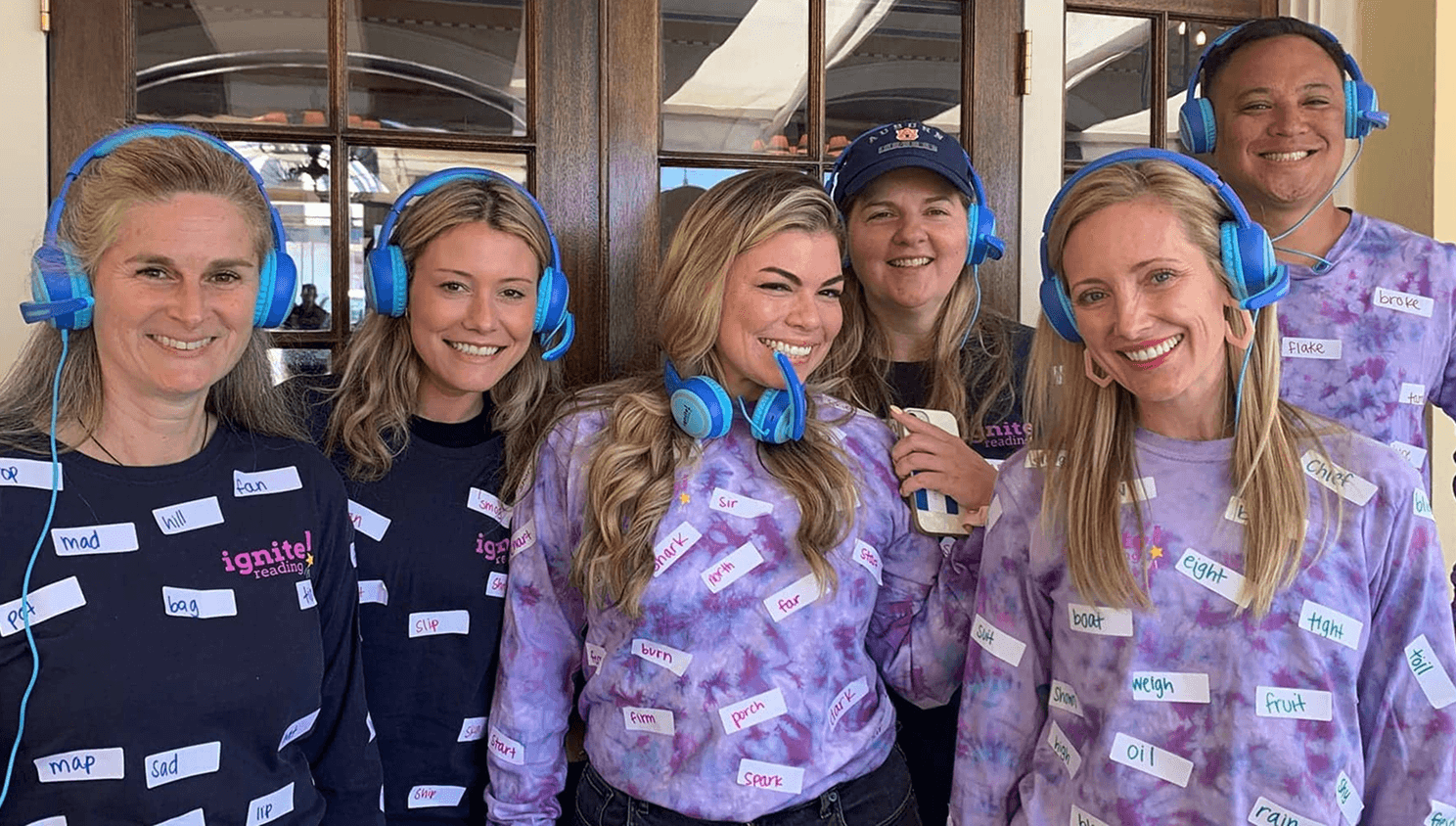 Six people wearing headphones and labeled shirts
