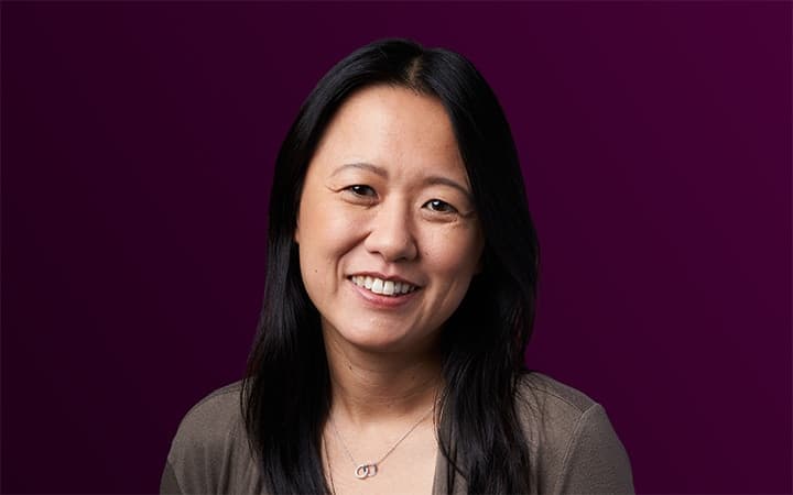 Smiling person on a purple background.