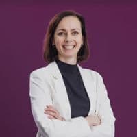 Small portrait of a person in a white blazer with arms crossed