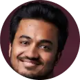 Tiny circular portrait of a smiling person against burgundy
